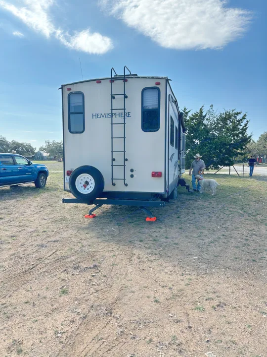 Hemisphere travel trailer RV rental set up in a rural setting, with a blue truck, a man, and a white dog.. Forest River Salem Hemisphere Lite 2015