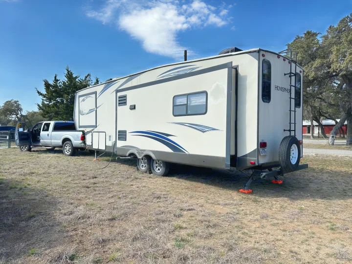 A spacious RV rental (travel trailer) and a silver pickup truck parked on a dry, grassy field.. Forest River Salem Hemisphere Lite 2015