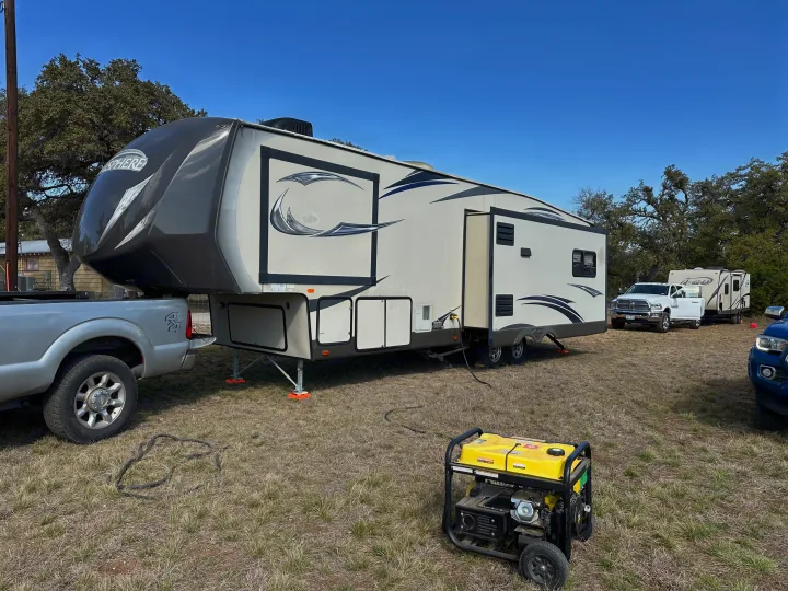 Large fifth-wheel RV, supported by jacks and powered by a generator, with its tow truck nearby. Ideal rv rental setup.. Forest River Salem Hemisphere Lite 2015
