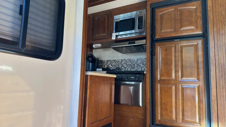 Inside an RV rental: a well-equipped kitchen with microwave, stove, oven, fridge, and ample storage.. Forest River Salem Hemisphere Lite 2015
