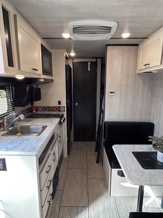 Well-equipped RV rental interior showcasing a compact kitchen and cozy dinette area, ideal for road trips.. Genesis Supreme 16 BB 2024