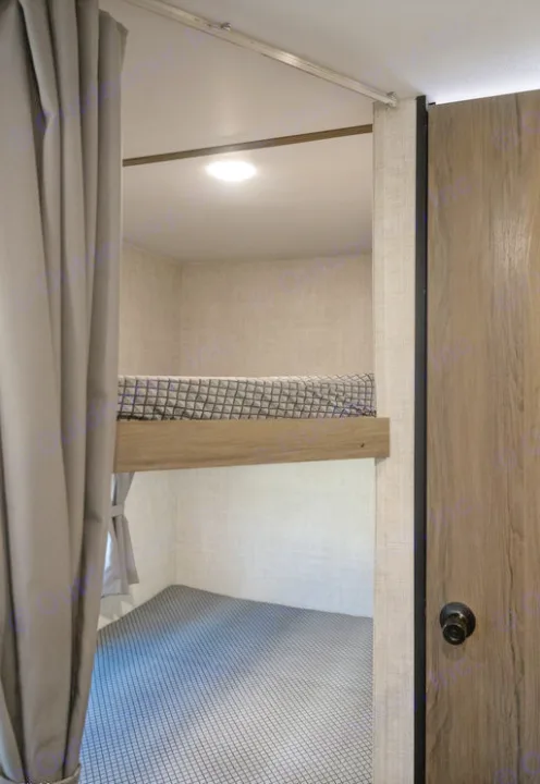 Compact RV rental interior featuring a cozy upper bunk bed with light and a lower sleeping/play area, perfect for family adventures.. Gulf Stream 248BH 2022