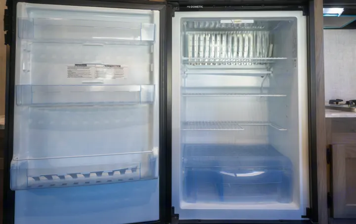 A clean, empty Dometic refrigerator with open doors, ready for an RV rental adventure. Shows shelves, freezer, and crisper.. Gulf Stream 248BH 2022