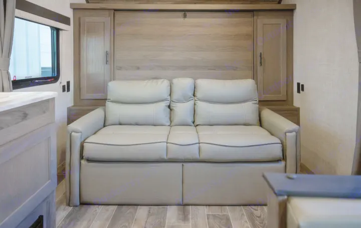 Inside this RV rental: a gray sofa converts to a bed, set against wood cabinets. Perfect for flexible RV living.. Gulf Stream 248BH 2022