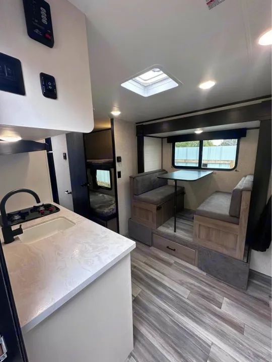 Bright RV rental showcasing a modern kitchen with sink & stove, comfy dinette, and bunk beds. Clean, spacious interior.. Jayco Jay Flight SLX 2024