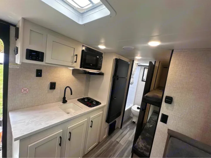 Modern RV rental interior: compact kitchen, bunk beds, and bathroom for comfortable travel.. Jayco Jay Flight SLX 2024