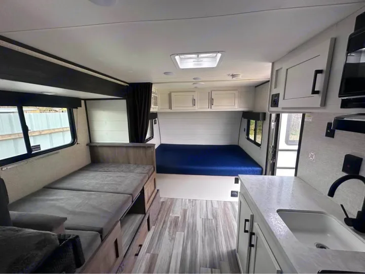Bright RV rental interior: A bed, convertible bench seating, and a compact kitchen offer a cozy travel space.. Jayco Jay Flight SLX 2024