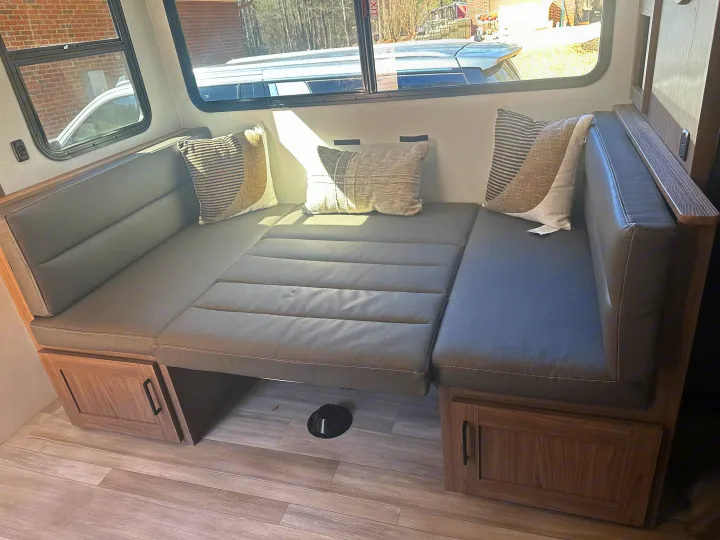Comfortable RV rental interior with a versatile dinette that converts to a bed, complete with cozy cushions and ample storage.. Alliance RV Delta 251BH 2024