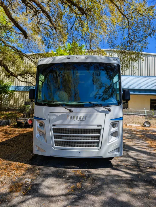 White Pursuit by Coachmen RV motorhome for your next rv rental adventure. Front view showing tree reflections.. Coachmen Pursuit 2022
