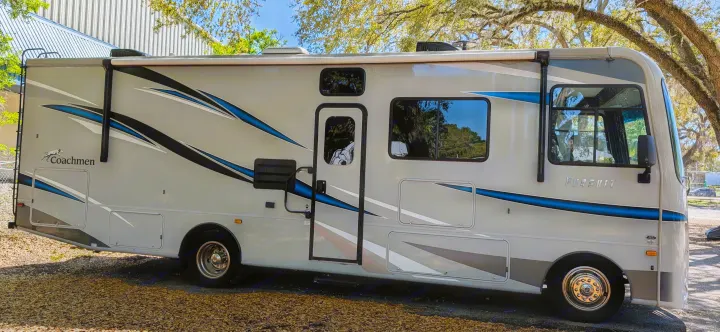 Light-colored Coachmen Pursuit Class A motorhome RV rental with distinctive black and blue stripes.. Coachmen Pursuit 2022