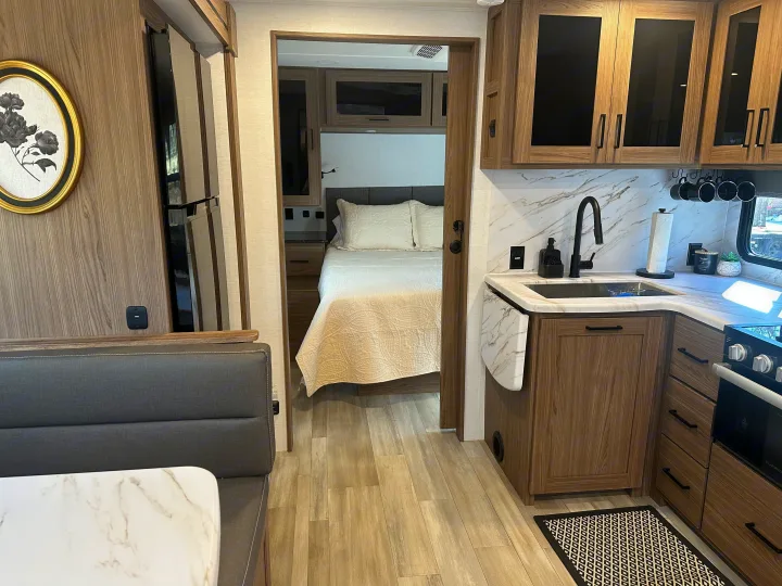 Modern RV rental interior: compact kitchen, cozy dining booth, and inviting bedroom setup.. Alliance RV Delta 251BH 2024