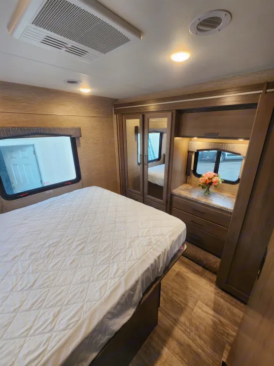 Spacious RV rental bedroom with queen bed, ample storage, and two large windows for a comfortable stay.. Thor Motor Coach Chateau 2023
