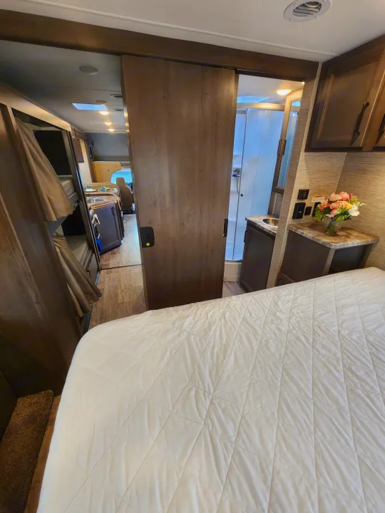 RV rental interior: View of a comfortable bedroom, sliding door to bunks, and bathroom; kitchen/dining visible beyond.. Thor Motor Coach Chateau 2023