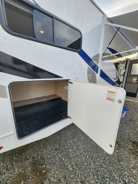 Explore this RV rental's accessible exterior storage bay, showcasing ample space for gear. Note the side window and illuminated awning.. Thor Motor Coach Chateau 2023