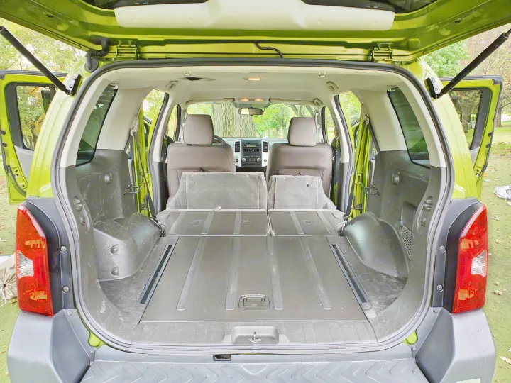 Interior of a lime green SUV, showing its spacious cargo area with folded seats, great for an rv rental.. Nissan XTerra 2012