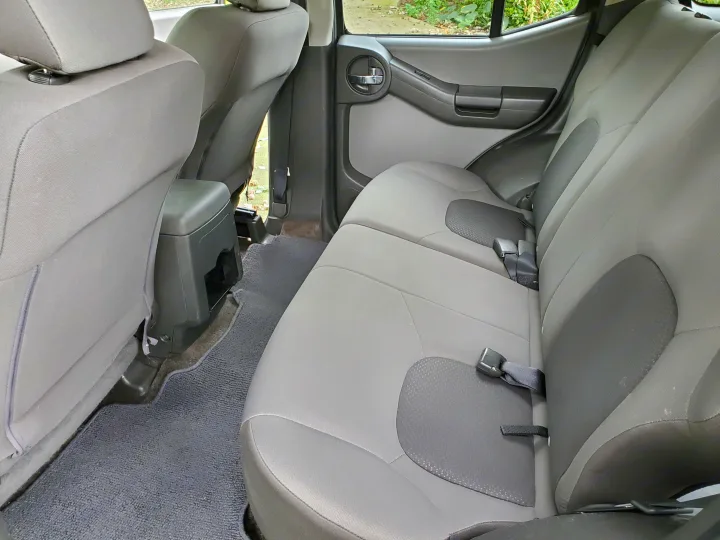 Neat grey fabric rear seats and floor of a vehicle, providing ample space for your next RV rental trip.. Nissan XTerra 2012