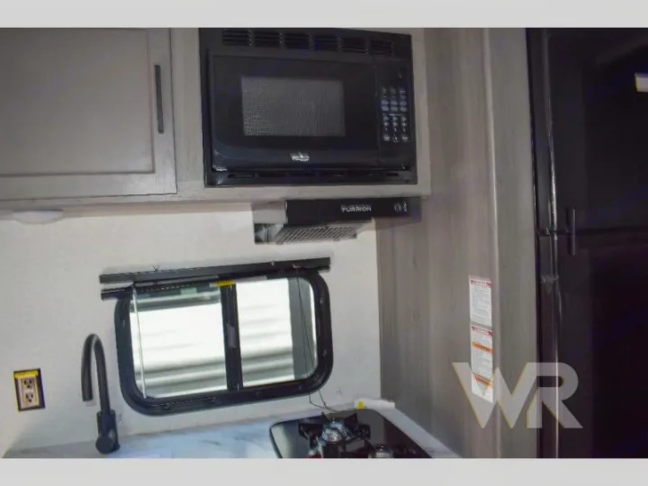 RV rental kitchen: Microwave, range hood, sink, stovetop, and compact refrigerator amenities.. Keystone RV Hideout Sport 2024