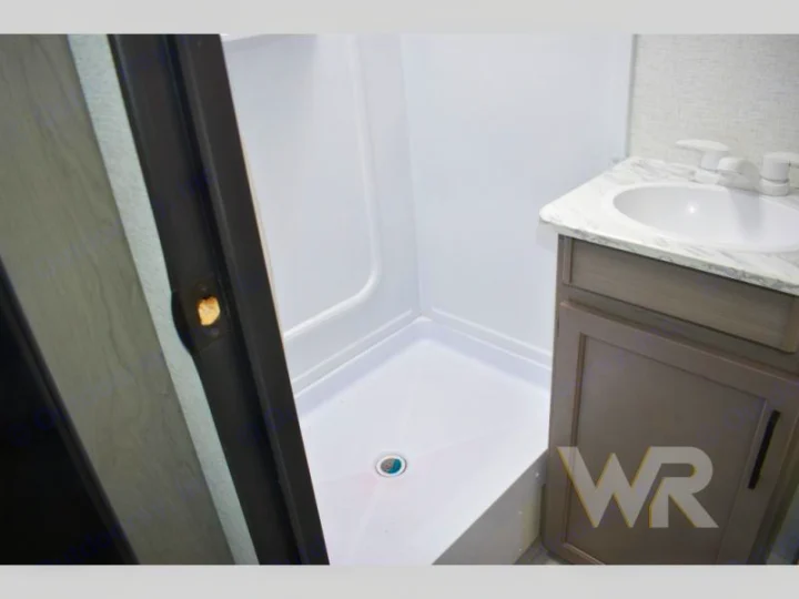 Compact RV rental bathroom with white shower stall, vanity, and sink. Perfect for your road adventure.. Keystone RV Hideout Sport 2024