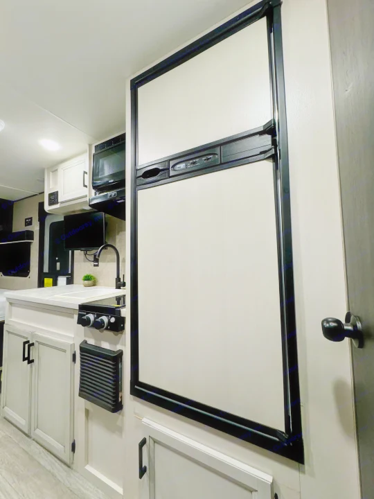 Compact and modern RV rental kitchen featuring a large refrigerator, microwave, and stove for convenient travel.. Jayco Jay Flight SLX 2022