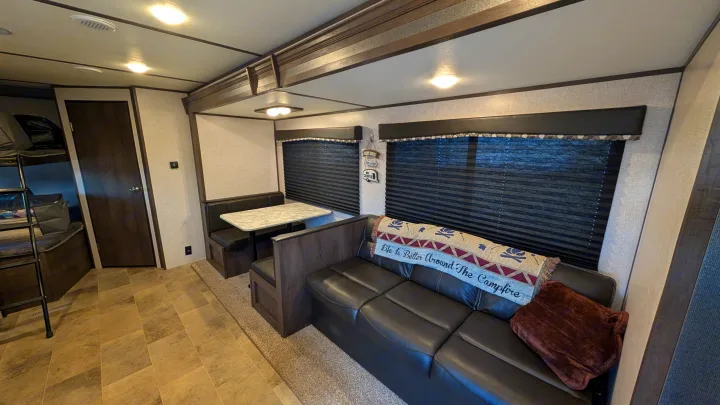 Inside this cozy RV rental: a comfortable living area with sofa, dinette booth, and a sleeping nook with bunk beds.. Dutchmen Coleman Lantern LT 2021