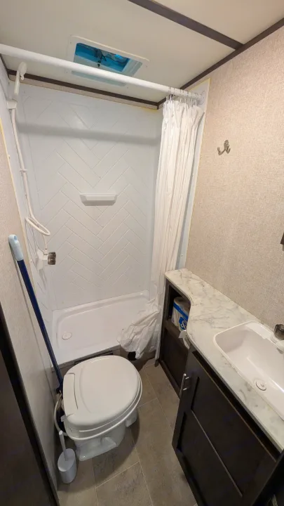 RV rental bathroom: A compact space with a white herringbone shower, toilet, and vanity with sink.. Dutchmen Coleman Lantern LT 2021