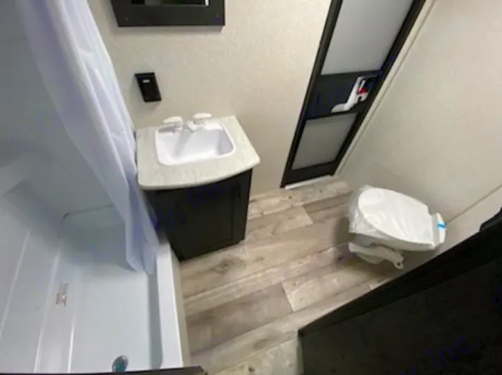 Compact RV rental bathroom features a shower, sink, and toilet, maximizing space for comfortable travel.. KZ 332BHKSE 2022