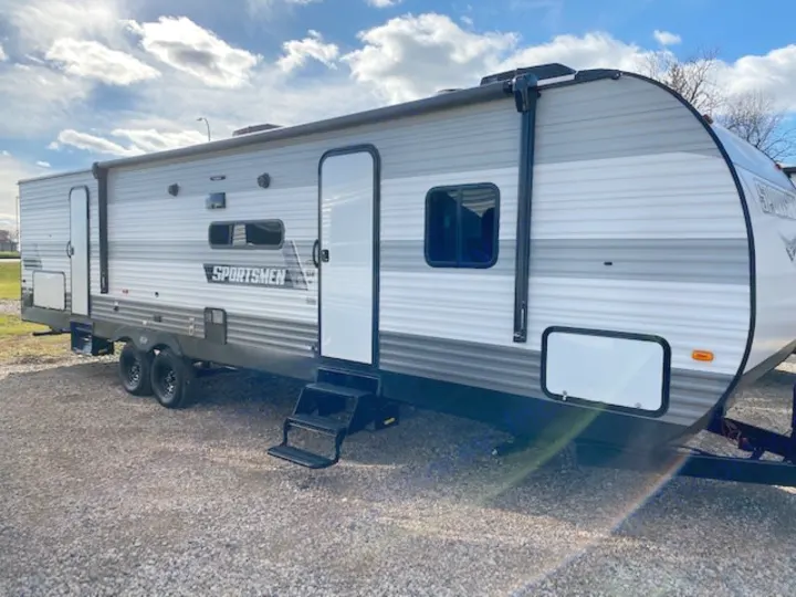 This gray & white travel trailer is a great option for your next rv rental adventure. Parked on gravel under blue skies.. KZ 332BHKSE 2022