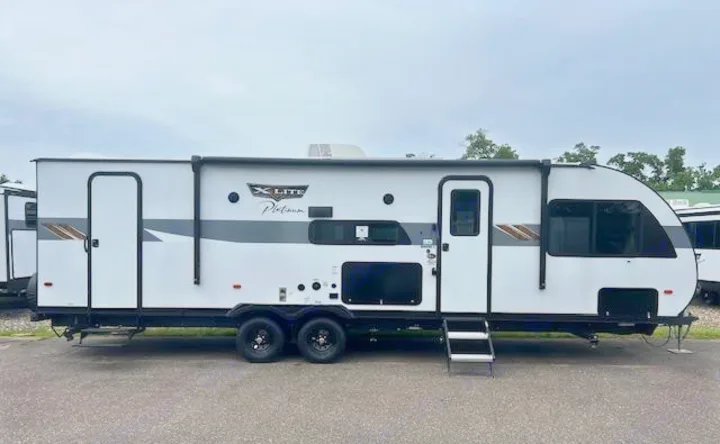 White X-LITE Platinum travel trailer RV rental, parked outdoors with entry steps extended.. Forest River Wildwood X-Lite Platinum 2024