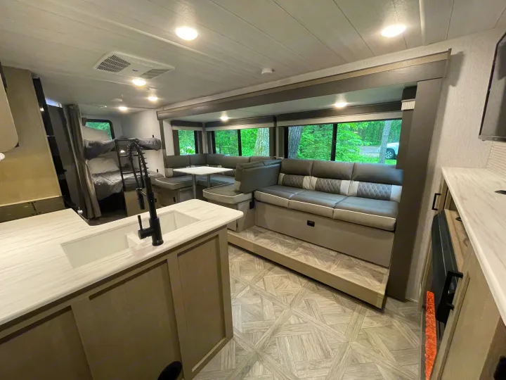 Spacious RV rental interior with a kitchen, U-shaped dinette, lounge, and bunk beds, ideal for camper adventures.. Forest River Wildwood X-Lite Platinum 2024