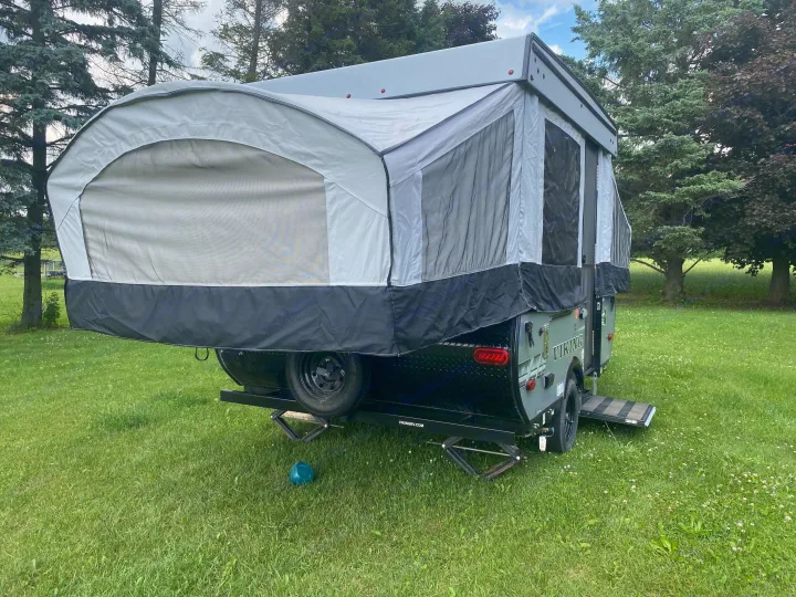 RV rental: A cozy pop-up camper, fully set up in a lush grassy field, ready for your next outdoor adventure.. Coachmen epic 1906 2019