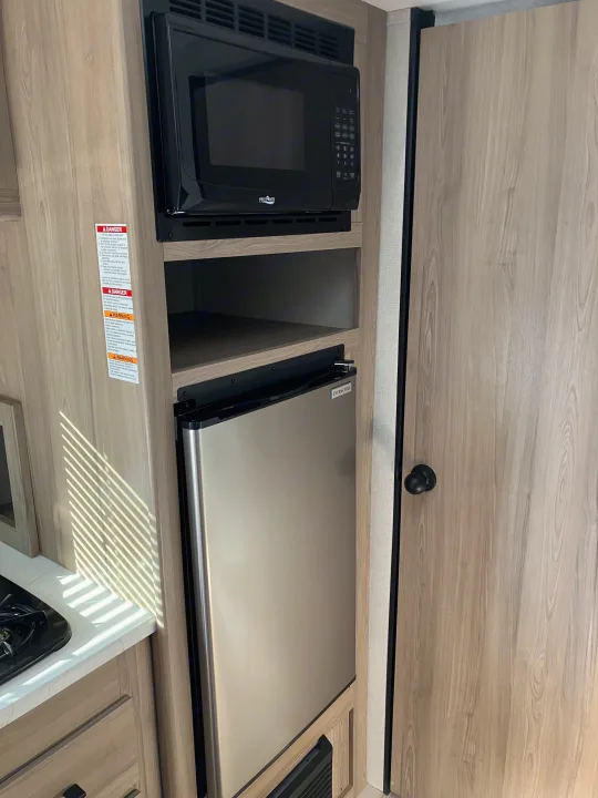 RV rental interior kitchen featuring a High Pointe microwave, Ever Chill refrigerator, and cabinet space, ideal for travel.. Coleman 17B 2025