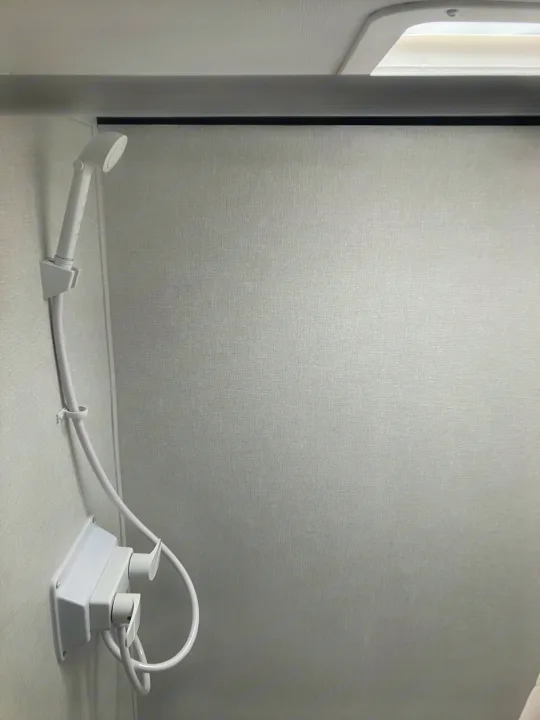 Compact RV rental bathroom showcasing a white handheld shower with simple controls for a clean, functional space.. Coleman 17B 2025