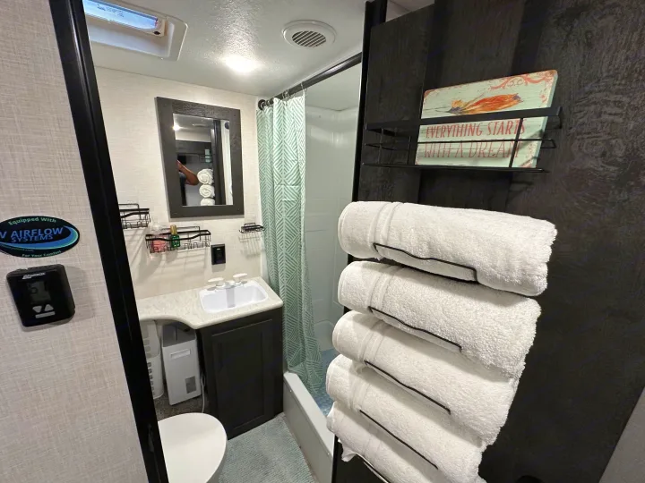 This well-appointed RV rental bathroom features a compact sink, toilet, shower, and organized towel storage. Perfect for road trips.. K-Z Manufacturing Sportsmen 2023