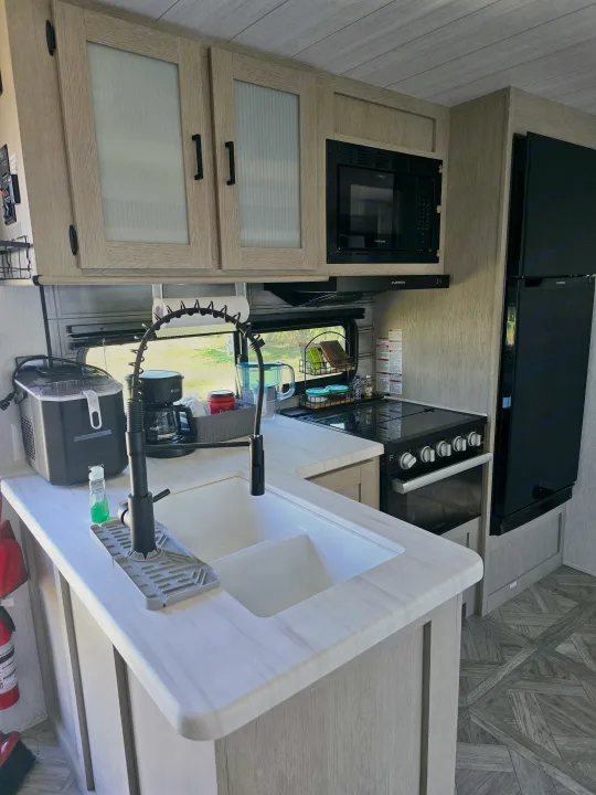 Spacious RV kitchen w/ modern light wood cabinets, sink, microwave, oven, fridge, & ice maker. Great for RV rental!. Forest River Salem Platinum 2024