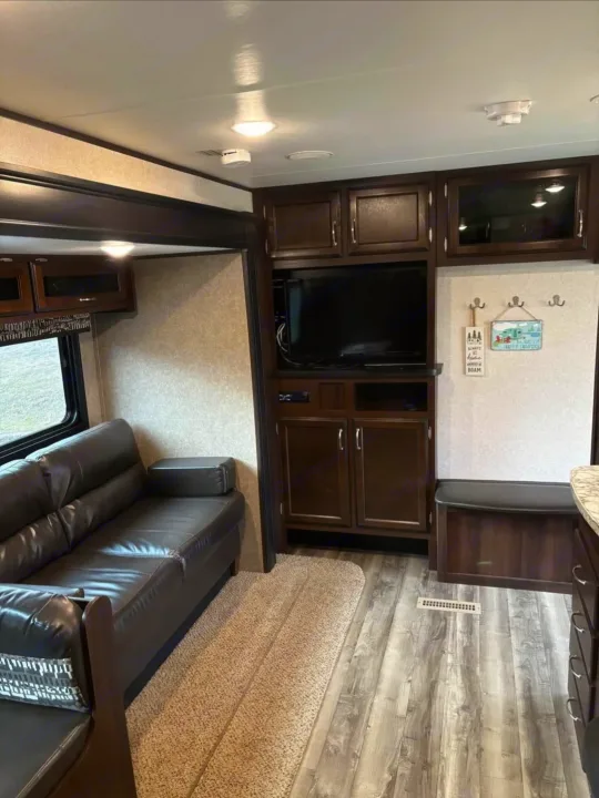 Spacious RV rental living area featuring a dark leather sofa, entertainment center with TV, and comfortable dinette bench.. Jayco Jay Flight SLX 2018