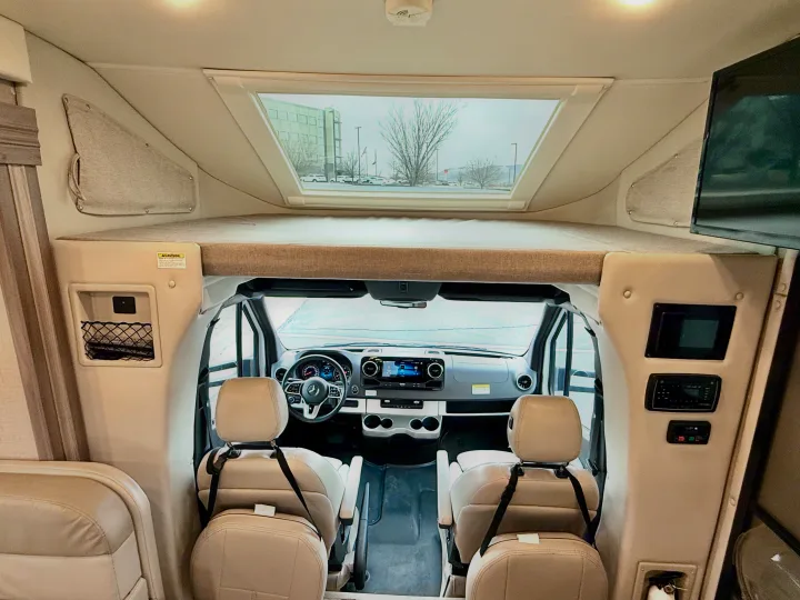 Inside an RV rental: view of cockpit dashboard, overhead sleeping bunk, and utility controls. Bright & functional interior.. Thor Tiburon 2022