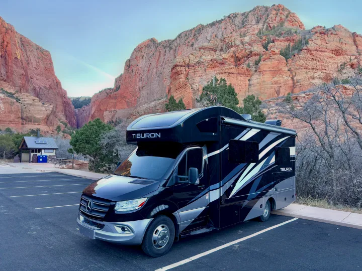 Sleek black/silver Tiburon RV rental by towering red rock formations.. Thor Tiburon 2022