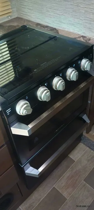 A black Furrion range with a glass cooktop and oven in an RV rental, offering convenient cooking.. Thor Motor Coach Chateau 2021