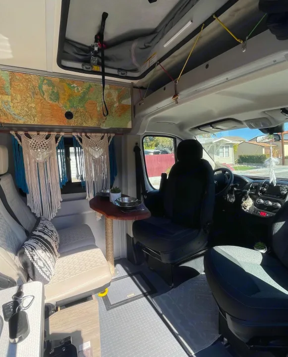 Step inside this cozy rv rental: a stylish camper van interior with a living area, small dining table, and front cab.. Dodge Winnebago 2021