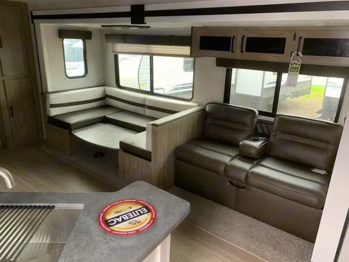 RV rental interior features a modern dinette, comfy theater seating, and a compact kitchen. Ideal for travel.. Forest River Palomino Puma XLE 2022