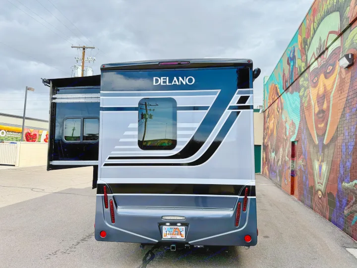 Rear view of a Delano RV rental, slide-out extended, parked next to a colorful mural.. Thor Delano 2023