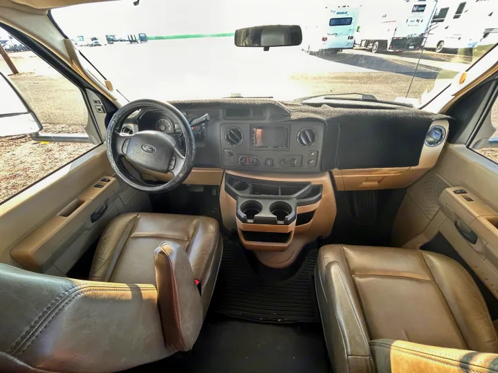 RV rental cockpit with beige leather seats, steering wheel, and dashboard, ready for your road trip adventure.. Forest River Sunseeker 2017