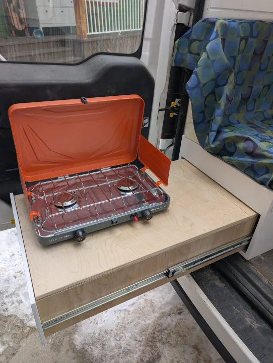RV rental: Orange GSI Outdoors stove on a wood pull-out kitchen drawer, ideal for camper van cooking.. Dodge Sprinter Van 2015
