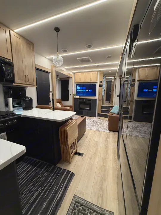 Modern RV rental interior with sleek kitchen, cozy living area, TV, and comfortable seating for travel adventures.. Heartland Cyclone 2025