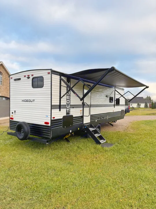 Ready for adventure! A white 'Hideout' travel trailer with awning extended, ideal for your next RV rental trip.. Keystone RV Hideout 2024