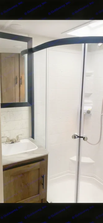 This RV rental features a modern, clean bathroom with a clear glass shower, a vanity sink, and a wall-mounted mirror.. Forest River Wildwood 2021