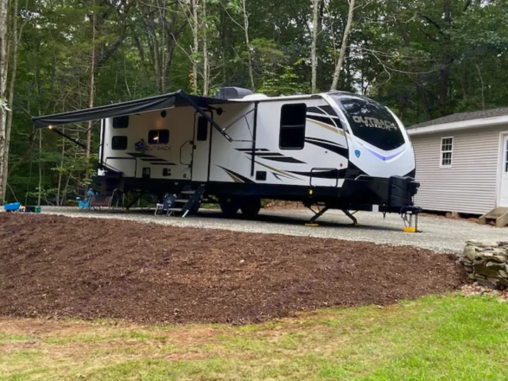 Outback rv rental parked in a tranquil wooded campsite with awning extended. Ready for your next outdoor adventure!. Keystone RV Outback Ultra-Lite 2021