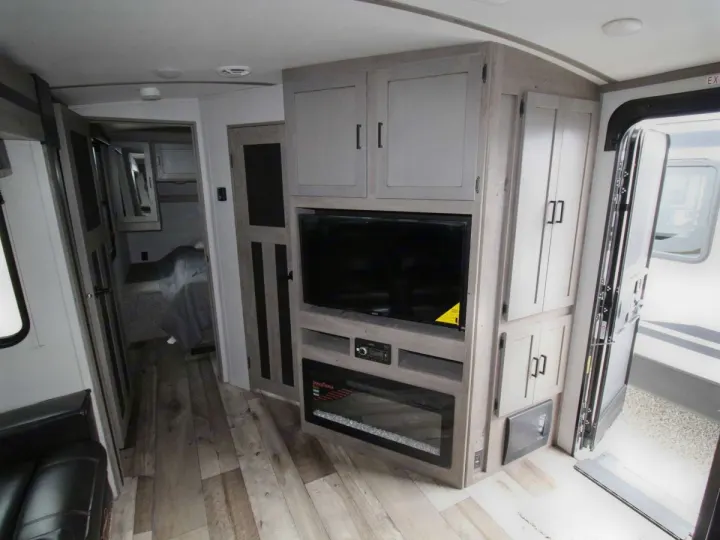 RV rental: Modern interior featuring TV, electric fireplace, light cabinets, and wood flooring near entrance.. Keystone RV Outback Ultra-Lite 2021