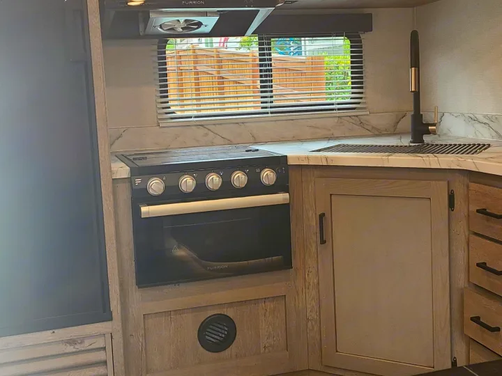 Well-equipped RV rental kitchen: Furrion stove, oven, sink, modern counters & cabinets. Compact and functional.. Keystone RV Outback Ultra-Lite 2021