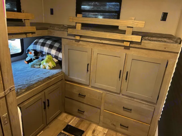 RV rental family bunk beds with built-in storage. Stuffed animals & pillow on lower bed.. Keystone RV Outback Ultra-Lite 2021
